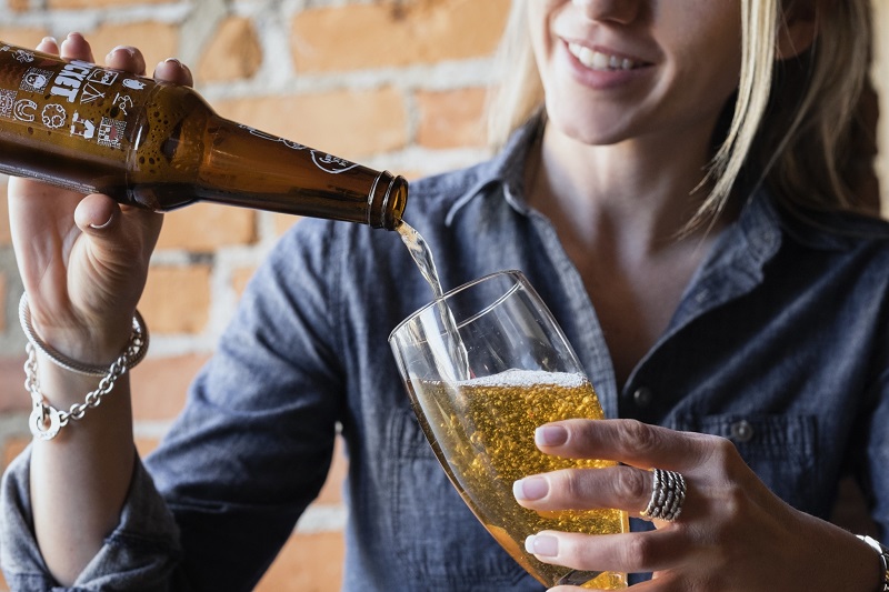 woman pouring beer into a glass from a beer bottle